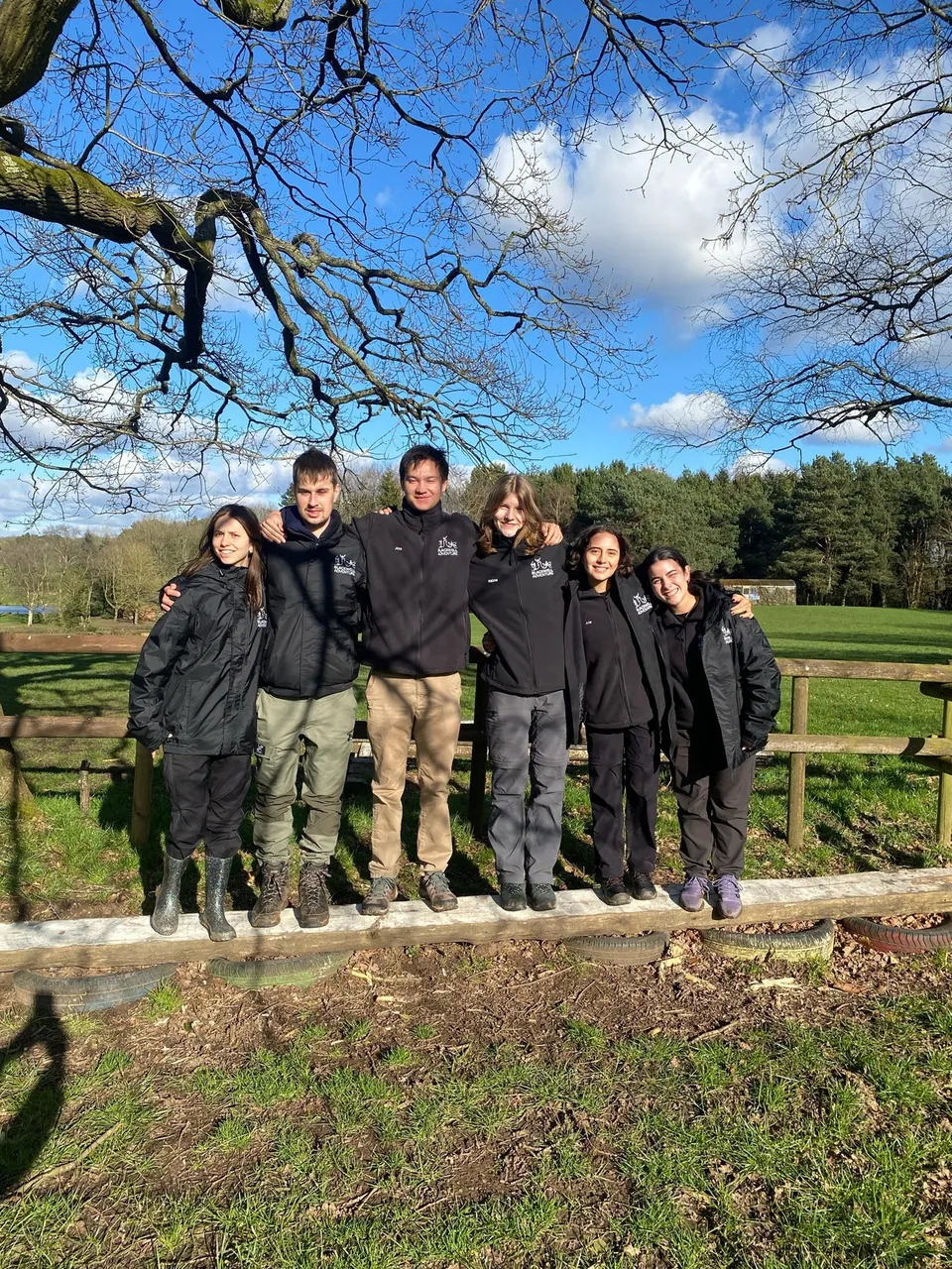 Grupo de participantes con ropa de abrigo en un prado de Blackwell Adventure, Inglaterra