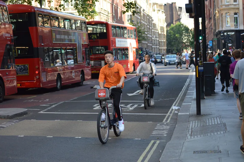 Buses rojos de dos pisos y ciclistas en una calle de Londres