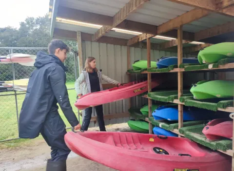 Participantes ordenando kayaks en un centro al aire libre