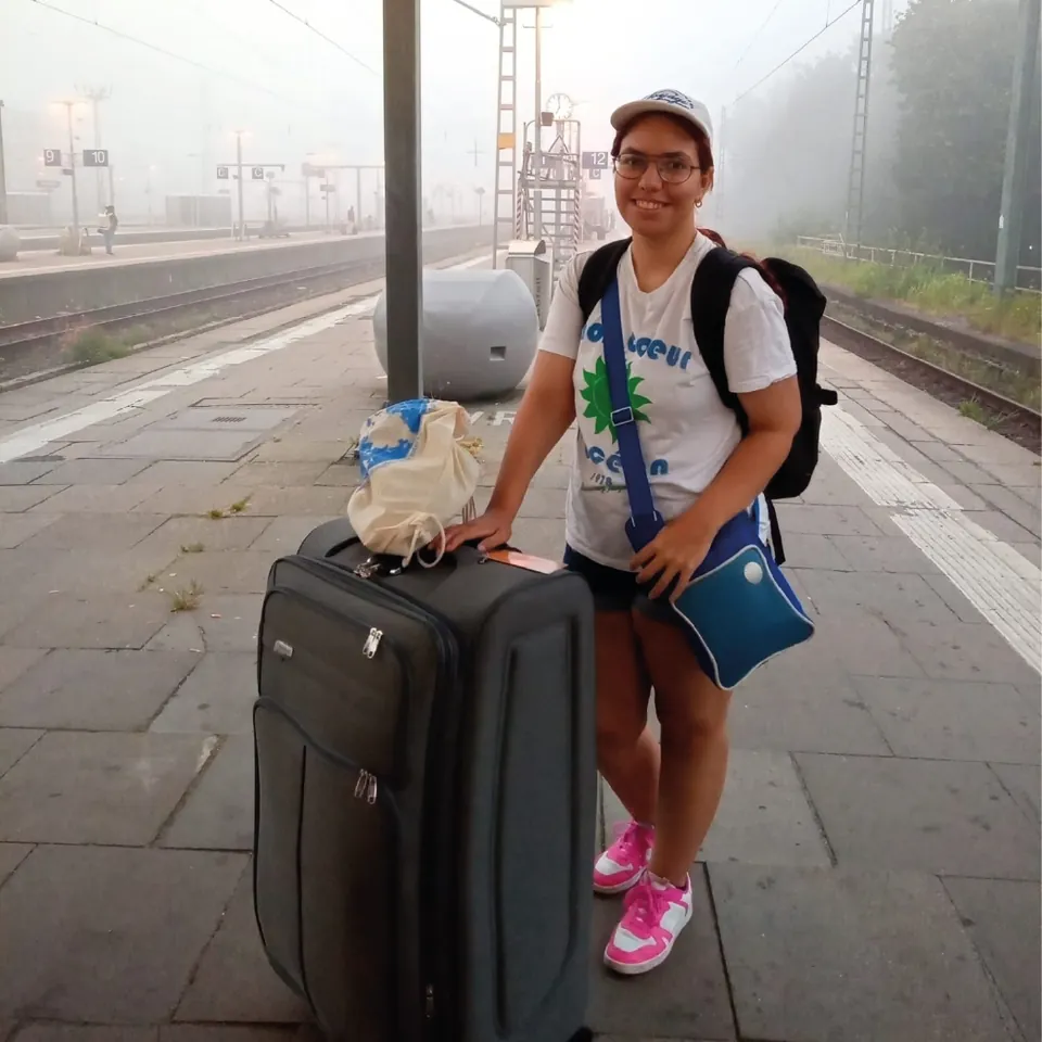 Participante con su maleta en el andén de una estación de tren