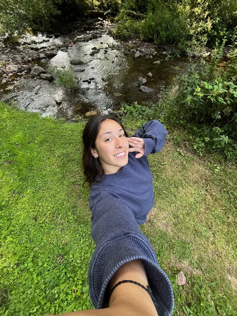 Valentina recostada en el pasto junto a un arroyo en Inglaterra